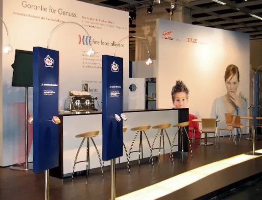Heller Messestand der fine food alliance mit Barhockern und großflächiger Bildwand