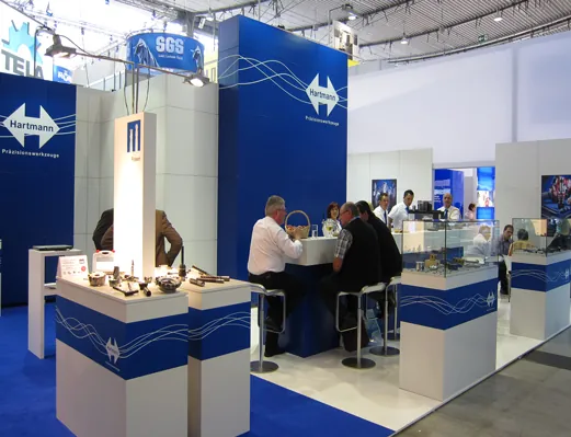 Großer blauer Hartmann Messestand mit Besprechungstheke und Gästen